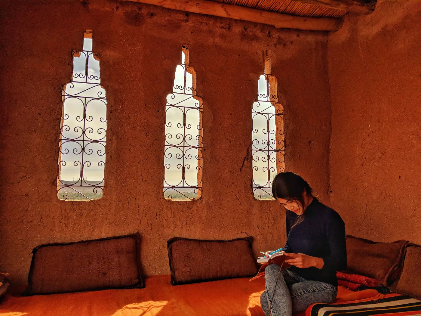 Mai-Lan Khong writing in a notebook, in a room with three arched windows